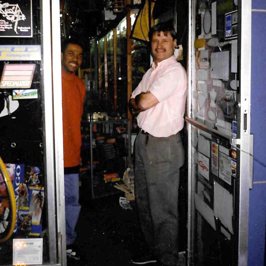 Philip Cabbad taking a phone call in the original R&A Cycles shop in Brooklyn, surrounded by Zefal pumps, CyclePro tubes, and Specialized products, circa early 1980s