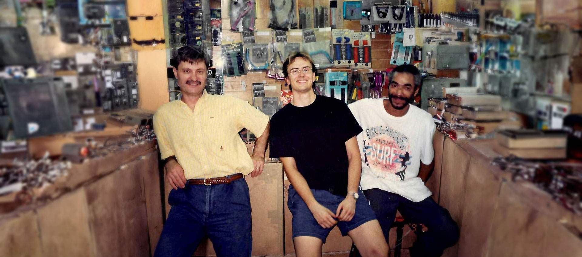 Close-up of Philip Cabbad in the original R&A Cycles shop, shelves stocked with CyclePro tubes and Zefal pumps, representing the shop's early focus on premium imported cycling products